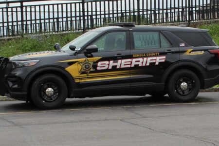 A black Seneca County Sheriff SUV with yellow and white lettering is parked on a paved surface.