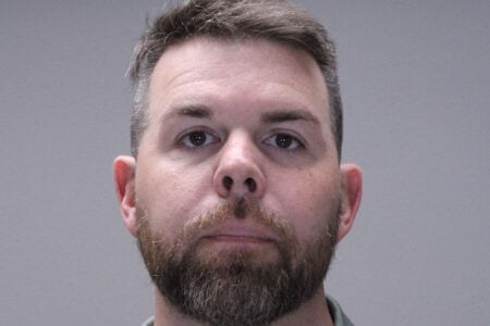 Mugshot of a bearded man with short hair against a plain gray background.
