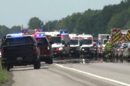 Emergency vehicles, including police, ambulances, and fire trucks, line a highway after a crash.