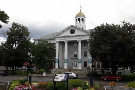 Auburn City Hall, a grand building with white columns, a clock tower, and a golden dome, surrounded by trees and landscaping.