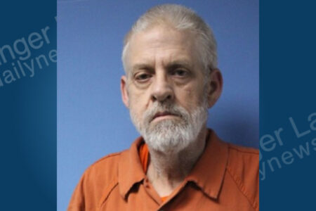 Mugshot of David Furman, a man with a white beard, wearing an orange jumpsuit against a blue background.