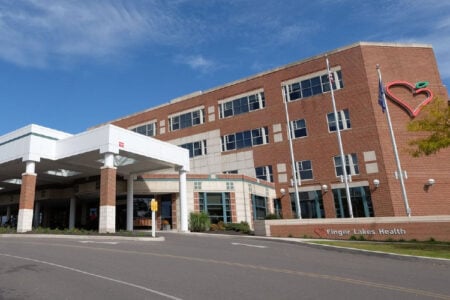 Exterior of the Finger Lakes Health building with a covered entrance and a large heart logo on a sunny day.