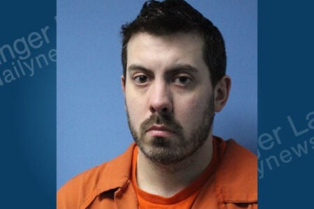 Mugshot of Joseph Lee Blair III, a man with dark hair and beard, wearing an orange jumpsuit against a blue background.