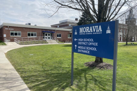 Moravia Central School District sign in front of a brick school building.
