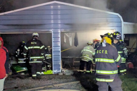 Firefighters from Oaks Corners Fire Department battle a shed fire, with smoke billowing from the structure.