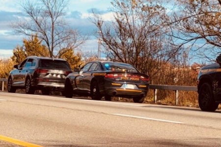 NY State Police car pulls over a dark SUV on the side of a road.