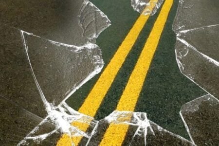 Shattered glass covers a road with double yellow lines, symbolizing an accident.