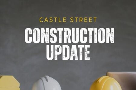 Text overlay reads "Castle Street Construction Update" above two hard hats on a desk with yellow graphic elements.