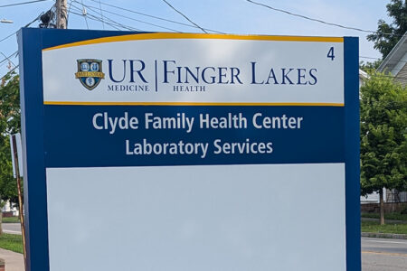A blue and white sign for UR Medicine Finger Lakes Health and Clyde Family Health Center Laboratory Services.