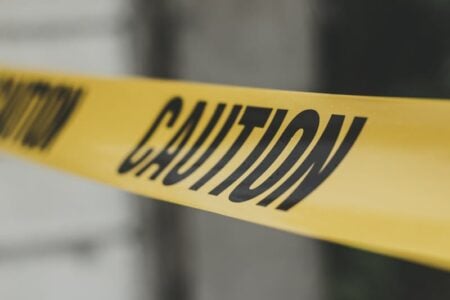Close-up of yellow caution tape with black 'CAUTION' lettering stretched across an out-of-focus background.