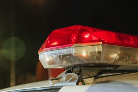 Close-up of a police vehicle's red and clear emergency light bar, illuminated at night.