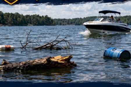 A motorboat navigates debris and a barrel in a Finger Lakes waterway.