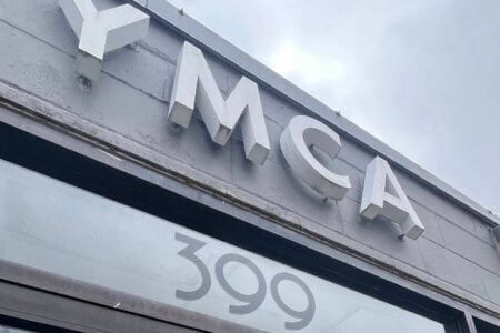 YMCA building exterior with "YMCA" sign on a grey wall and "399" displayed on the front window.