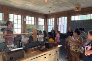 A docent shows vintage electrical equipment to a group of young people at the Case Research Lab in Auburn.