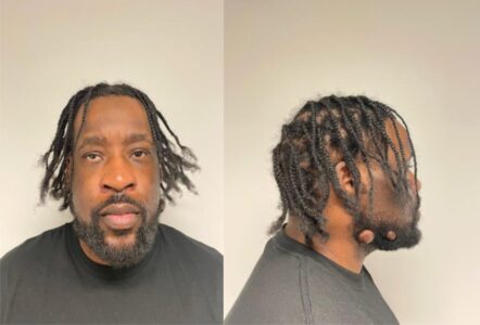Mugshot: Man with braids in front and side profile against a light background.