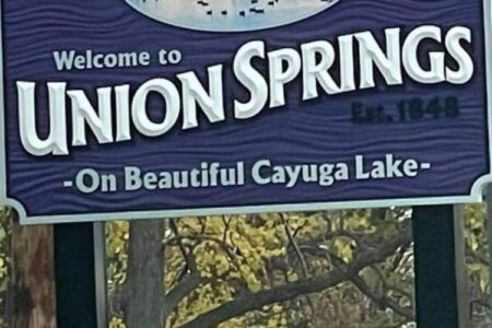 Welcome to Union Springs sign, on Cayuga Lake, is shown against a background of trees.
