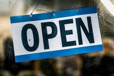 Blue and white "OPEN" sign hangs in a window, indicating a Finger Lakes business is open.