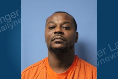 Mugshot of a Black man in an orange uniform, with short hair and a beard, looking directly at the camera.