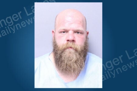 Bald man with a full brown beard wearing a light blue uniform shirt in a mugshot.