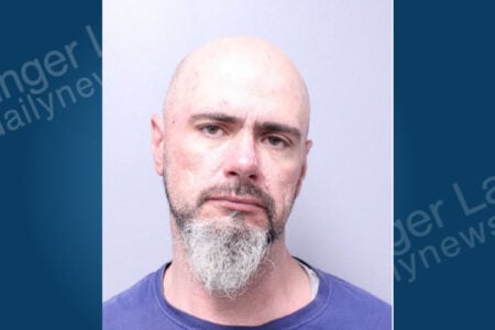 Bald man with a gray beard and dark shirt looks directly at camera in a mugshot.