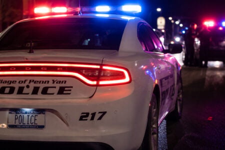 Rear view of a Village of Penn Yan Police car with flashing red and blue lights on a street at night.