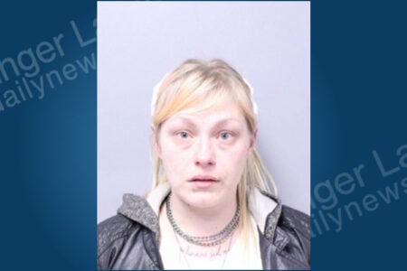 Blonde woman in a black jacket and white headband faces the camera for a mugshot.