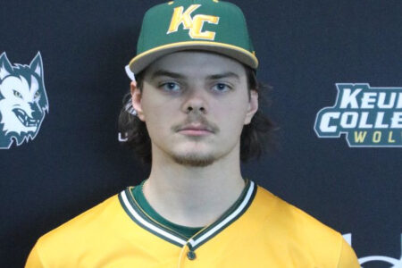Young man in a yellow and dark green baseball uniform and Keuka College Wolves cap poses against a dark backdrop.