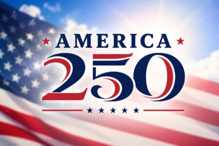 America 250 logo in red and blue over a blurred US flag and bright blue sky.