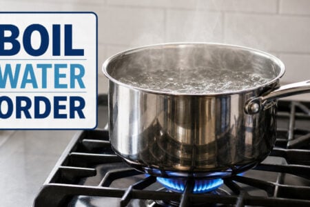 A pot of water boils on a gas stove burner with a "BOIL WATER ORDER" graphic displayed.