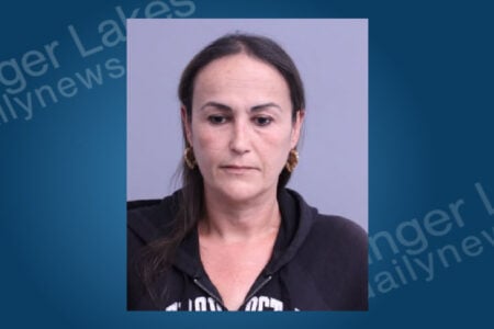 Woman with dark hair, black hoodie, and gold hoop earrings looks directly at the camera in a mugshot.