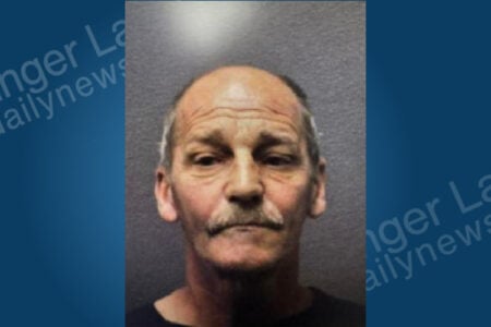 Mugshot of a balding man with graying hair and a mustache, wearing a dark shirt, looking at the camera.