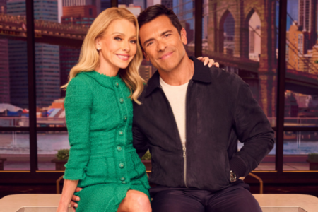 Kelly Ripa and Mark Consuelos smile, posing in front of a New York City skyline with the Brooklyn Bridge.