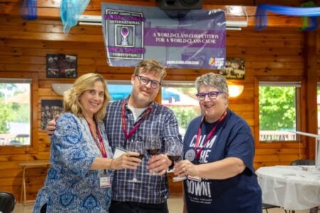 Three smiling judges toast with red wine at the Camp Good Days Finger Lakes International Wine & Spirits Competition.