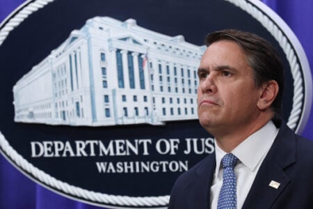 Assistant Attorney General Matthew G. Olsen looks serious in front of the Department of Justice seal.
