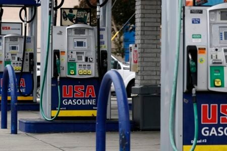 A row of USA Gasoline pumps, displaying fuel grades and prices, at a gas station.