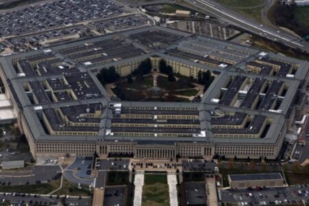 Aerial view of the Pentagon building, showing its five-sided shape, surrounded by parking lots and highways.