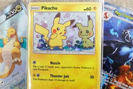 Three Pokémon trading cards featuring Dragonite, Pikachu, and Mega Charizard X, on a light surface.