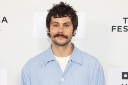 Dylan O'Brien with a mustache and light blue shirt poses at the Tribeca Festival.