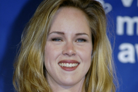Actress Rebecca De Mornay smiles at the camera against a blue "VMA Music Awards" background.