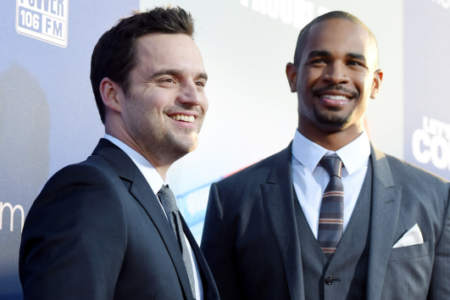 Actors Jake Johnson and Damon Wayans Jr. smile in suits at the "Let's Be Cops" premiere.
