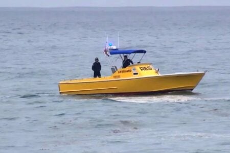 Yellow lifeguard boat with two crew members navigating Finger Lakes waters.