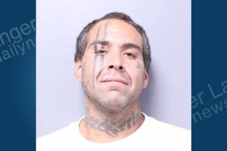 Mugshot of a man with facial tattoos, including vertical streaks over his left eye and "reck pride" on his neck, staring forward.