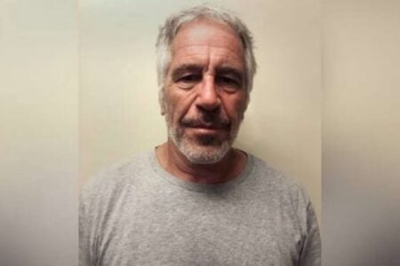 Jeffrey Epstein, a man with gray hair and a beard, looks straight ahead in a booking photo.