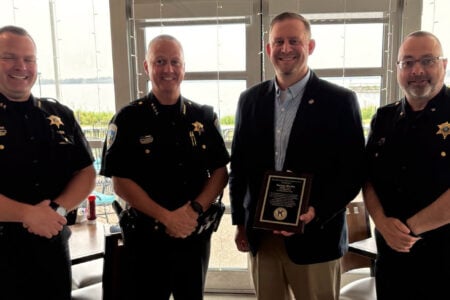 Three Ontario County Sheriff's officers and Nathan Martin receiving a Kiwanis award, smiling by a lake view.