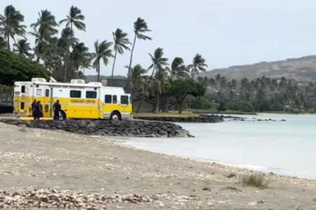 Honolulu Fire Dept Command Center vehicle and crew on a sandy beach with palm trees and calm water.