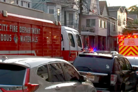 Jersey City Fire Department hazardous materials truck and ambulance with flashing lights on a residential street.