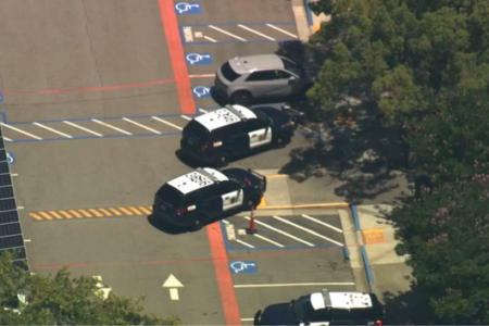 Aerial view of multiple police SUVs parked in a parking lot next to solar panels and trees.