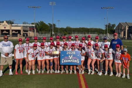 Penn Yan Lacrosse team members and coaches celebrate their 2026 V Championship on a sunny field.