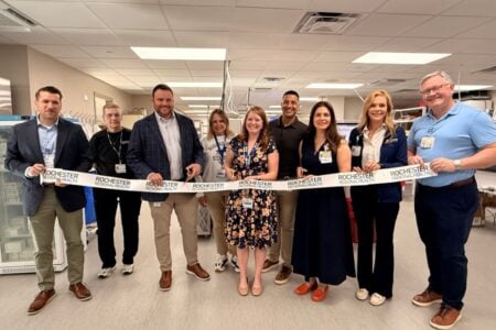 Nine Rochester Regional Health personnel cut a ribbon for a new facility opening ceremony.
