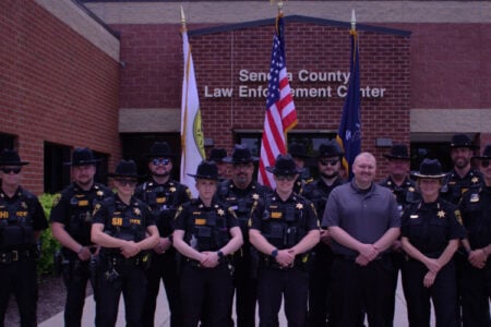 Group of Seneca County Sheriff's deputies and a man pose in front of the Law Enforcement Center.